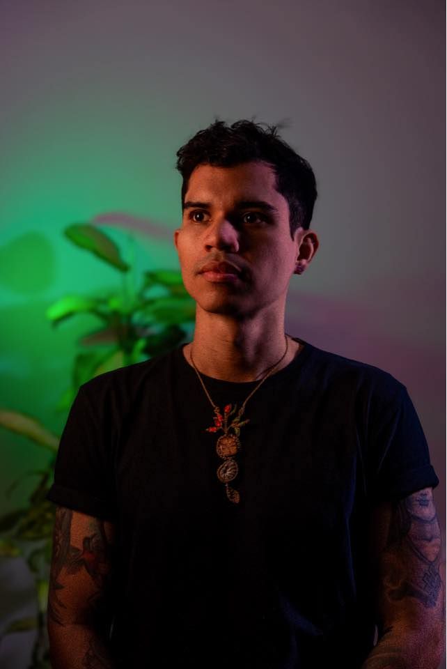 Retrato de Edward Torres, con plantas y luz verde al fondo